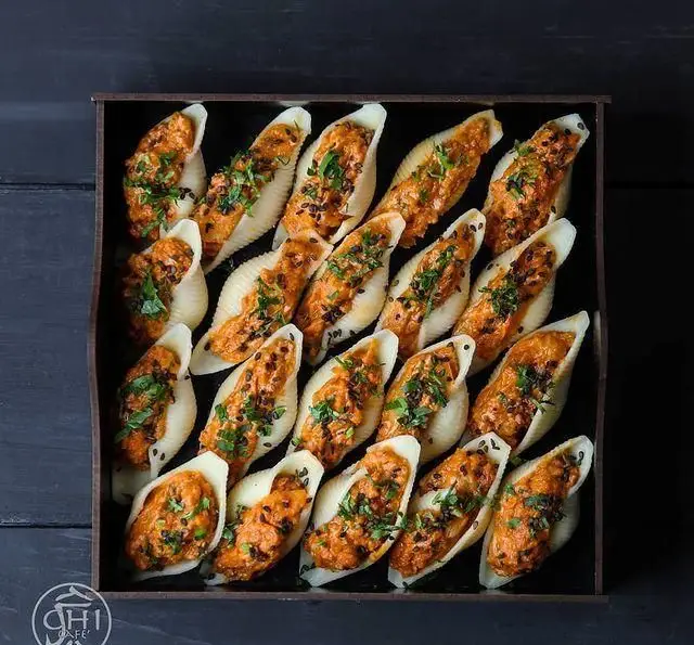 سینی جذاب چی کافه شامل پاستا کونکلیه شکم پر با سس نارنجی، سبزیجات معطر و کنجد سیاه، مناسب پذیرایی و مهمانی.