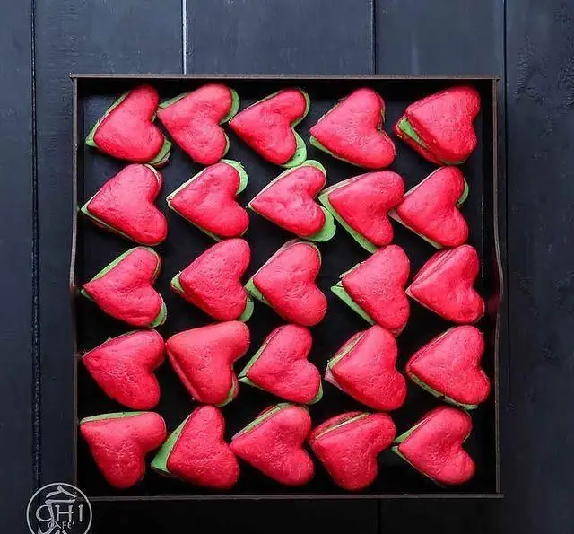 سینی جذاب پر از شیرینی‌های قلبی قرمز و سبز چی کافه. این ماکارون‌های خوشمزه و زیبا برای ولنتاین یا هدیه عالی هستند.