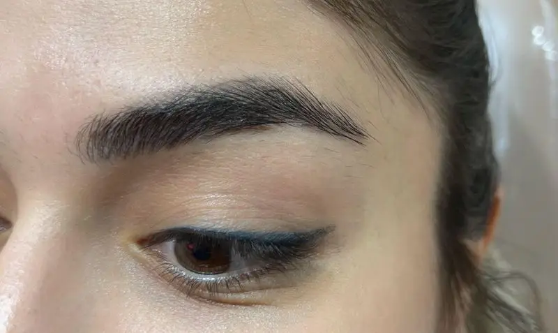 ابروی پرپشت و مرتب، خط چشم ظریف آبی و پوست صاف مشتری در سالن زیبایی کیانا، نشان‌دهنده خدمات تخصصی آرایش و مراقبت پوست است.
