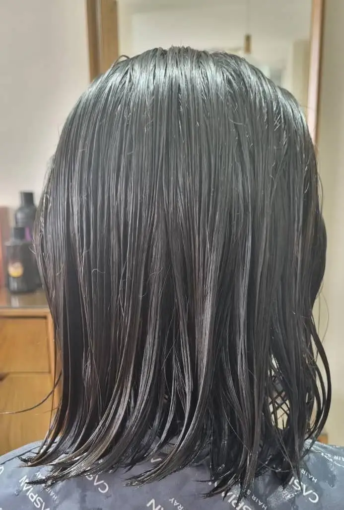 موی تیره و خیس مشتری در سالن زیبایی کیانا، آماده برای کوتاهی جدید یا دریافت خدمات تخصصی ترمیم و مراقبت از مو.