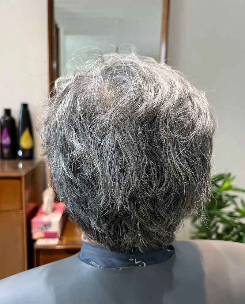 نمایی از پشت سر مشتری با موهای خاکستری طبیعی و کوتاه، آماده دریافت مدل موی شیک و خدمات حرفه‌ای در سالن زیبایی و اپیلاسیون کیانا.