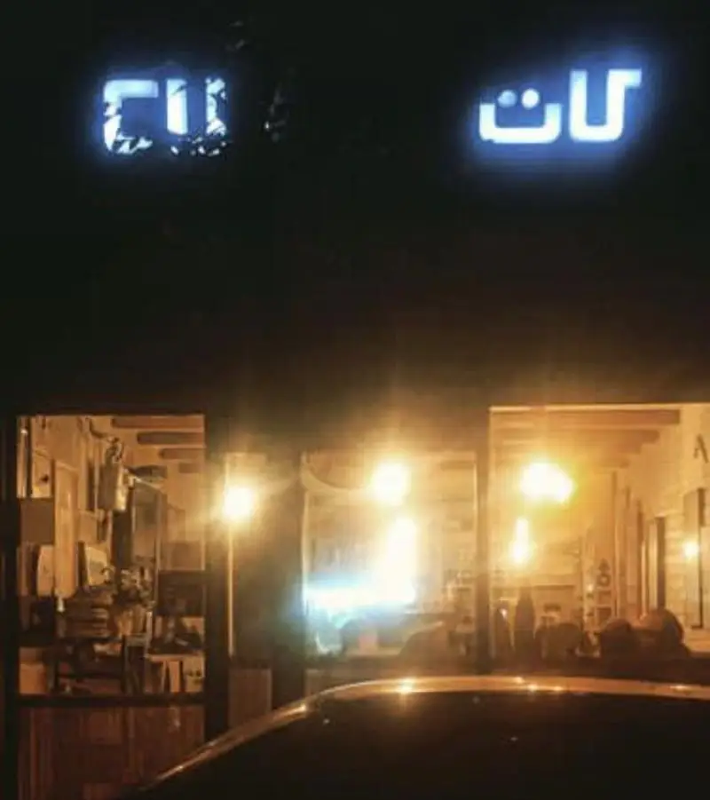 نمای بیرونی کافه کات در شب با تابلوی نورانی 'کافه کات'، نشان دهنده یک کسب و کار پر جنب و جوش و دلپذیر.