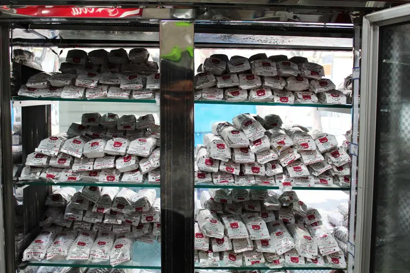 نمایی از ویترین فست فود ژامبونک، مملو از ساندویچ‌های تازه و خوشمزه، همگی در بسته‌بندی‌های سفید و آماده ارائه به مشتریان گرسنه.