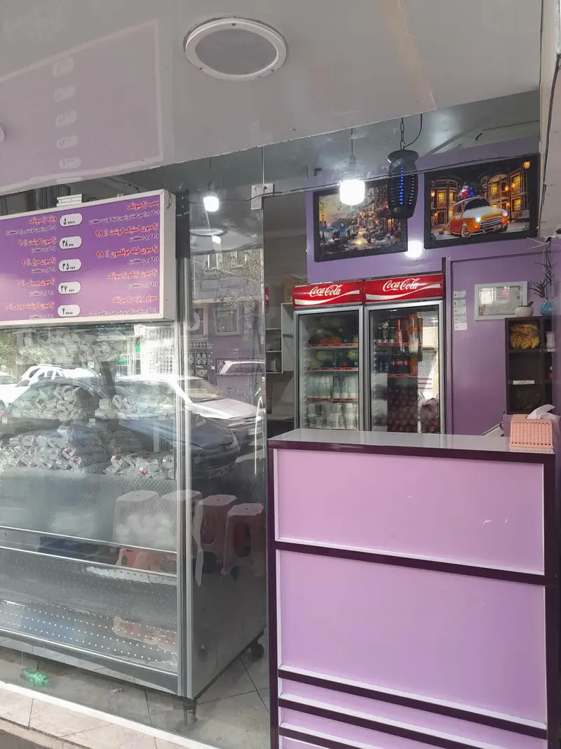 نمای داخلی فست فود ژامبونک، با تابلوی منو (قیمت ساندویچ‌های ژامبون)، ویترین، یخچال‌های کوکاکولا و پیشخوان بنفش مدرن.