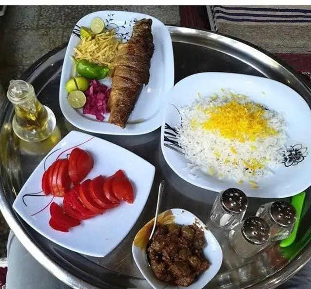غذای اصیل رستوران جویبار: ماهی سرخ شده با برنج زعفرانی، خورش، گوجه و سبزیجات تازه. یک تجربه لذت بخش برای ناهار و شام.
