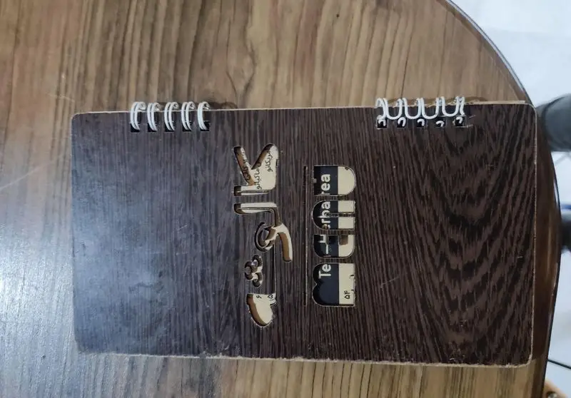 تصویر منوی چوبی خاص کافه سئول با حکاکی نام کافه، انواع قهوه (ماکیاتو، امریکانو) و بخش نوشیدنی.