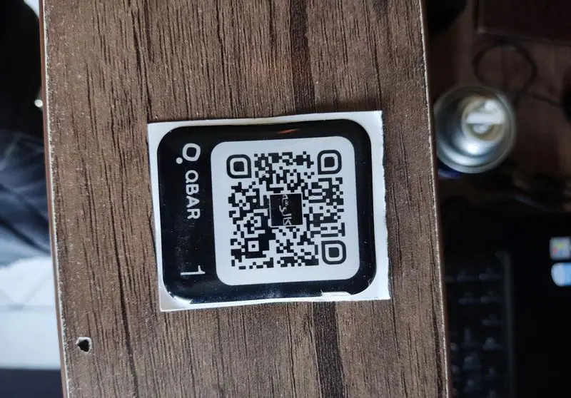 QR کد QBAR کافه سئول روی میز چوبی برای دسترسی آسان به منو و سفارش آنلاین، تجربه ای نوین و سریع در کافه سئول.