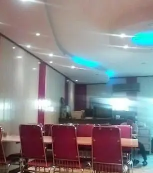 فضای داخلی دنج و مدرن کبابی فرد جوان با صندلی‌های قرمز، دیوارهای سفید و بنفش و نورپردازی شیک برای لذت بردن از کباب.