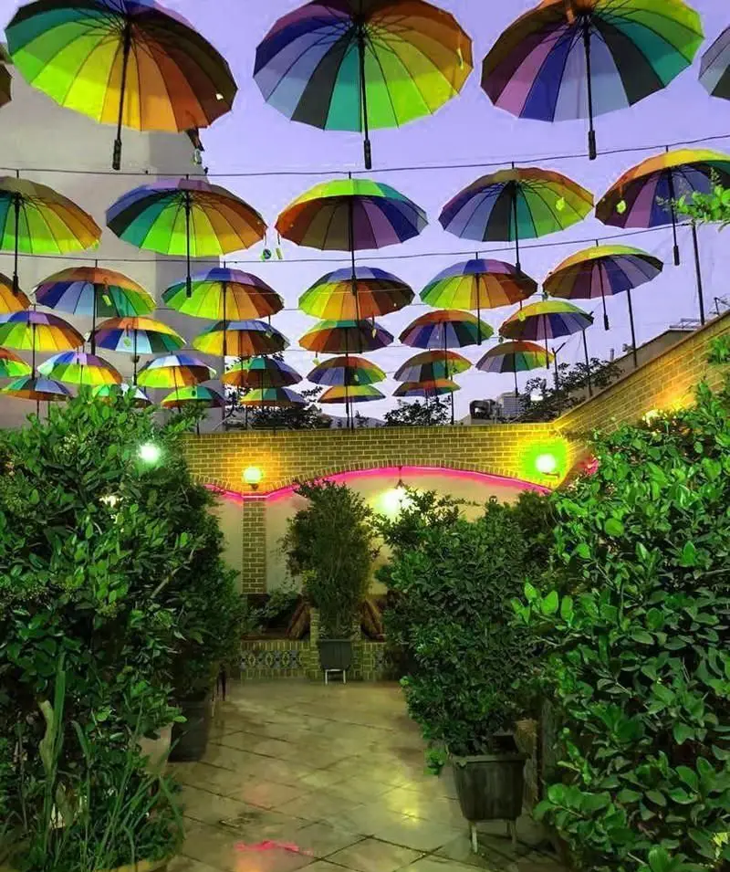 باغ رستوران حجت، رستوران ایرانی با فضای باز دلنشین و چترهای رنگی آویزان، دکوراسیون زیبا و محیطی سرسبز و آرامش‌بخش.