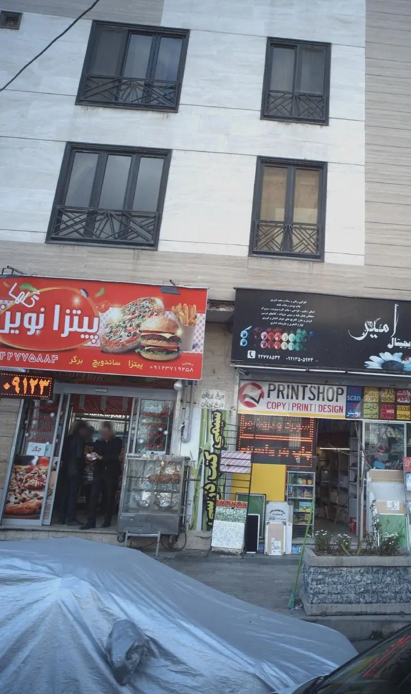 نمای خارجی کسب و کار پیتزا نوین، رستوران فست فود محبوب با تابلوی بزرگ پیتزا، ساندویچ و برگر. خدمات غذایی متنوعی ارائه می‌دهد.