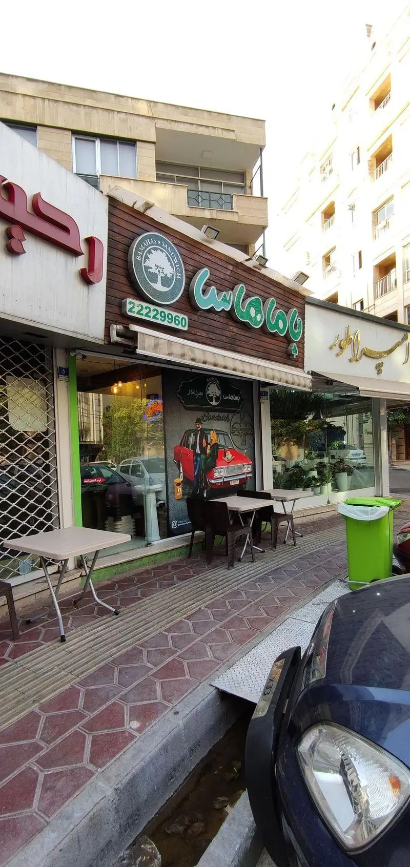 فست فود و ساندویچی باماهاس در تهران با نمای چوبی و تابلوی سبز رنگ. شامل میز و صندلی‌های بیرون و شماره تماس 22229960