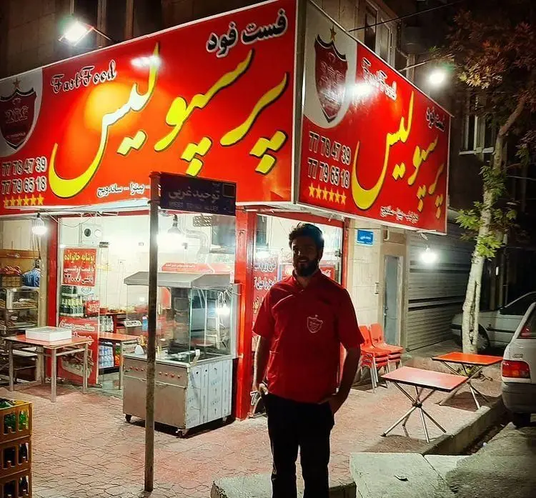 فست فود پرسپولیس در کوچه توحید غربی، با تابلوهای روشن و منوی پیتزا و ساندویچ. مردی در لباس پرسپولیس. تلفن: ۷۷۷۸۴۷۸۹، ۷۷۷۹۶۵۱۸.