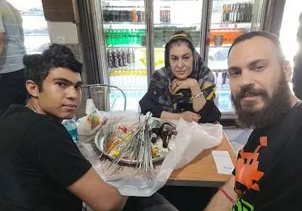 سه نفر از مشتریان جگرکی بهارنارنج، شامل یک جوان، خانم و آقا، در حال صرف کباب و جگر تازه به همراه نوشیدنی در محیطی گرم و دوستانه.