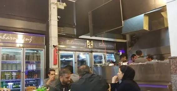 تصویری از فضای شلوغ و پرجنب‌وجوش جگرکی بهارنارنج، مشتریان در حال لذت بردن از غذا و یخچال‌هایی با محصولات متنوع.