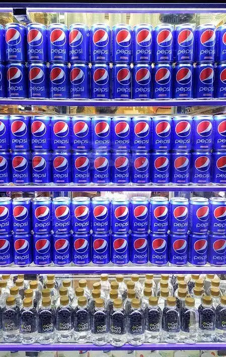 قفسه پر از نوشابه‌های پپسی و بطری‌های آب خنک در یخچال جگرکی بهارنارنج، مناسب برای رفع تشنگی بعد از کباب جگر.