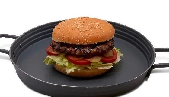 همبرگر بزرگ و آبدار رستوران گاردینو با نان کنجدی، پتی گوشت گریل شده، کاهو تازه، گوجه و خیارشور، روی سینی فلزی سیاه.