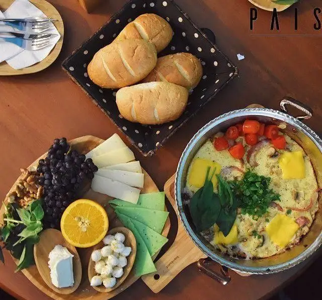 صبحانه کامل و رنگارنگ کافه پاییزا شامل املت مخصوص، انواع پنیر، نان تازه، میوه‌های تازه و مغز گردو.