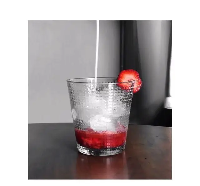 تهیه نوشیدنی جذاب و خنک توت فرنگی در کافه پاییزا. ریختن شیر روی توت فرنگی و یخ برای یک کوکتل میوه‌ای تازه و دلچسب.