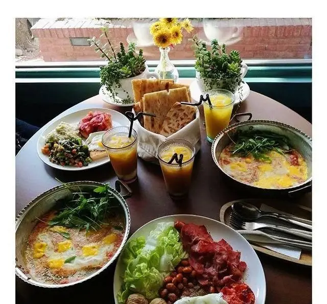 میز پر از غذاهای لذیذ صبحانه و برانچ کافه پاییزا: املت، نیمرو، بیکن، نان تازه، سالاد و آبمیوه در فضایی دلنشین.