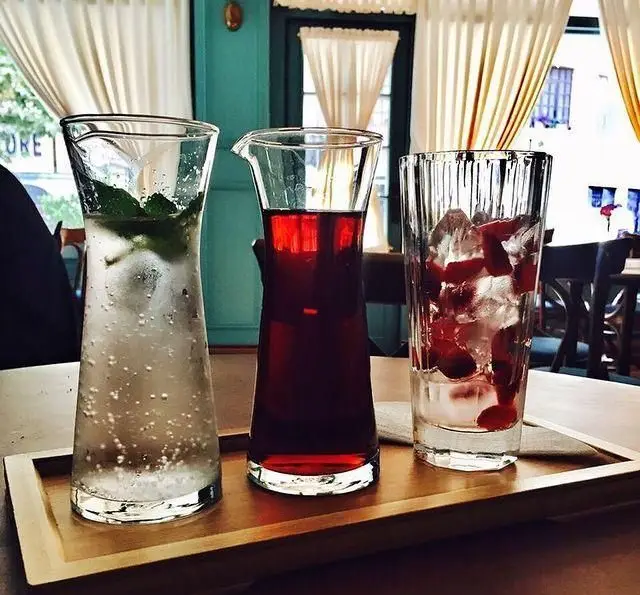 تجربه نوشیدنی‌های متنوع و خنک کافه پاییزا شامل آب گازدار، شربت طبیعی و نوشیدنی میوه‌ای با توت فرنگی در فضایی دلنشین.