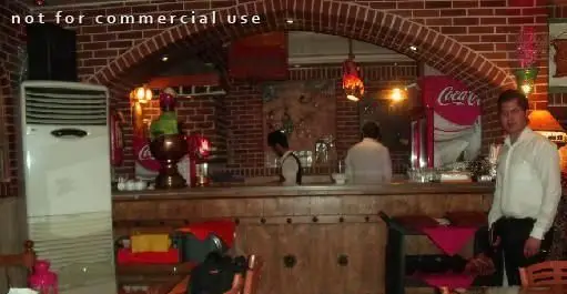 فضای داخلی گرم سفره خانه پارتیان با دیوارهای آجری و سقف طاقی، پیشخوان سنتی و حضور پرسنل آماده پذیرایی از مهمانان.