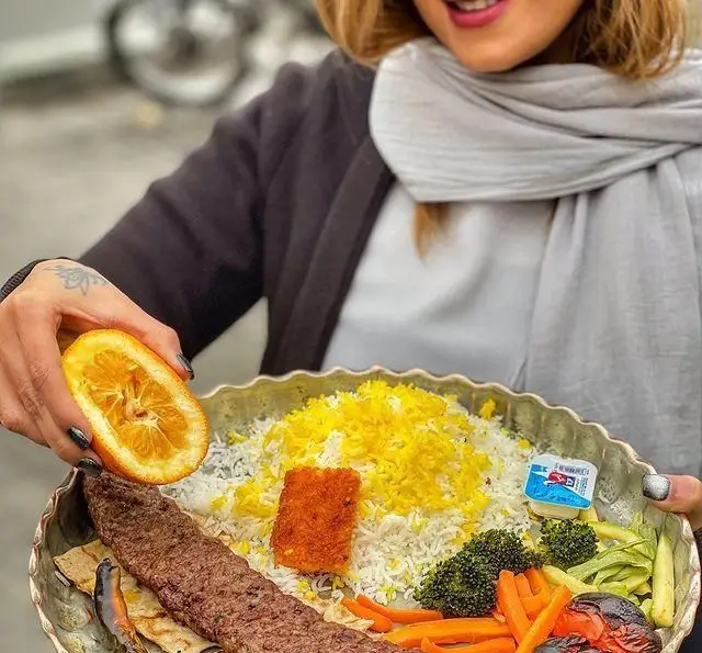 سینی چلو کباب کوبیده لذیذ رستوران گیلار با برنج زعفرانی، سبزیجات تازه، دورچین کامل و پرتقال برای طعم‌دهی، غذای ایرانی.