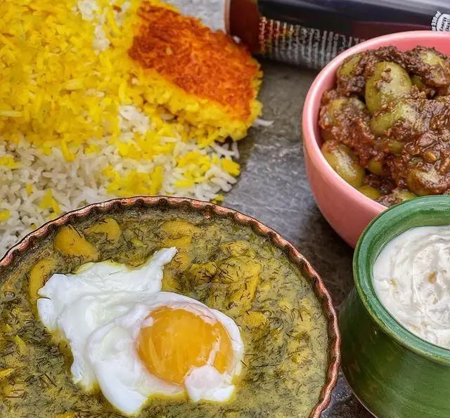 یک وعده غذای سنتی و لذیذ گیلانی شامل باقالی قاتوق با تخم مرغ، پلو ته دیگی و زیتون پرورده در رستوران گیلار.