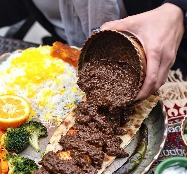 غذای اصیل ایرانی رستوران گیلار: خورش فسنجان ریخته شده روی کباب و نان، همراه با پلو زعفرانی و سبزیجات تازه.