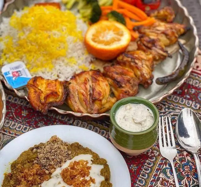 سفره غذای گیلانی رستوران گیلار شامل کباب جوجه، پلو زعفرانی، میرزاقاسمی با سیر و گردو و مخلفات تازه. تجربه طعم اصیل ایرانی.