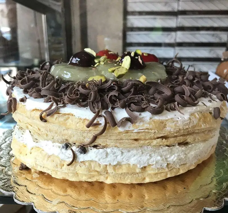 کیک لایه ای میل فوی (Mille-feuille) کافه قنادی لادن با خمیر هزارلا، خامه فراوان، فر شور شکلاتی، پسته و گیلاس روی ژله سبز، بهترین دسر و شیرینی.