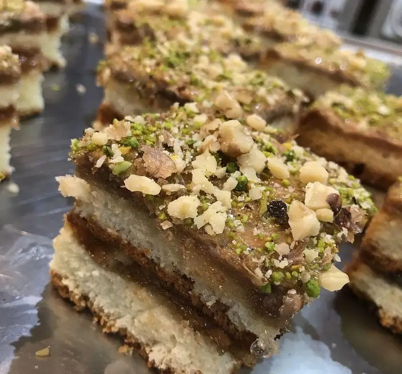 کافه قنادی لادن: شیرینی لایه ای مغزدار با تزئین پسته و گردو، انتخابی ایده‌آل برای لذت بردن از یک دسر خوشمزه و متفاوت.