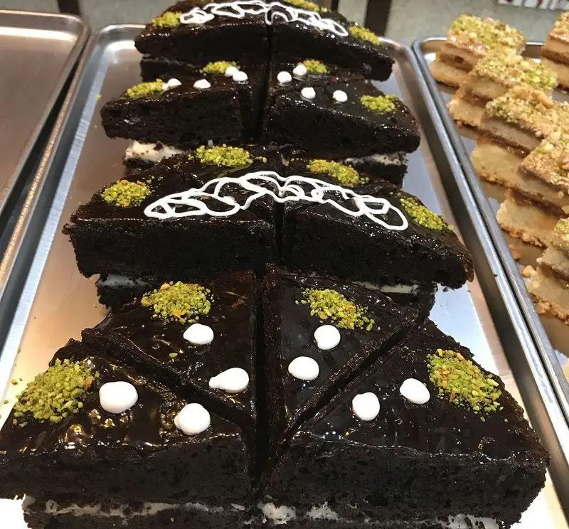 انواع کیک‌های شکلاتی تیره با پسته و خامه، و دسرهای تازه کافه قنادی لادن. بهترین شیرینی‌ و دسر فروشی در تهران.