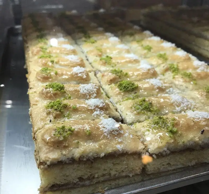 شیرینی‌های شربتی و کیک‌های سنتی کافه قنادی لادن، با تزیین جذاب پسته و نارگیل. دسرهای تازه و خوشمزه برای پذیرایی.