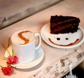 کافه چراغان بام لند، بهترین کافه تهران: قهوه لاته گرم با طرح S و کیک شکلاتی خوشمزه با لبخند. لحظاتی شیرین و دلنشین برای دسر و نوشیدنی در فضایی آرامش‌بخش و زیبا.