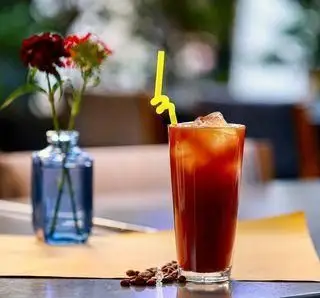 قهوه سرد خنک و گوارا با تکه‌های یخ و نی در کافه چراغان بام لند تهران. نوشیدنی تابستانی ایده‌آل برای لذت بردن از فضای دلنشین.