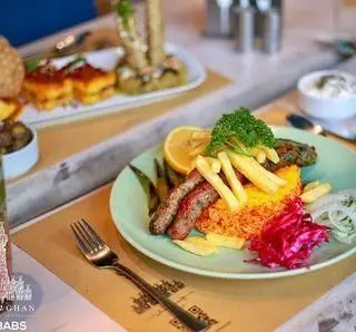 نمایی اشتهاآور از سرو کباب‌های خوشمزه ایرانی در کافه چراغان بام لند، همراه با پلو زعفرانی و دورچین متنوع. بهترین تجربه غذایی در رستوران بام لند.