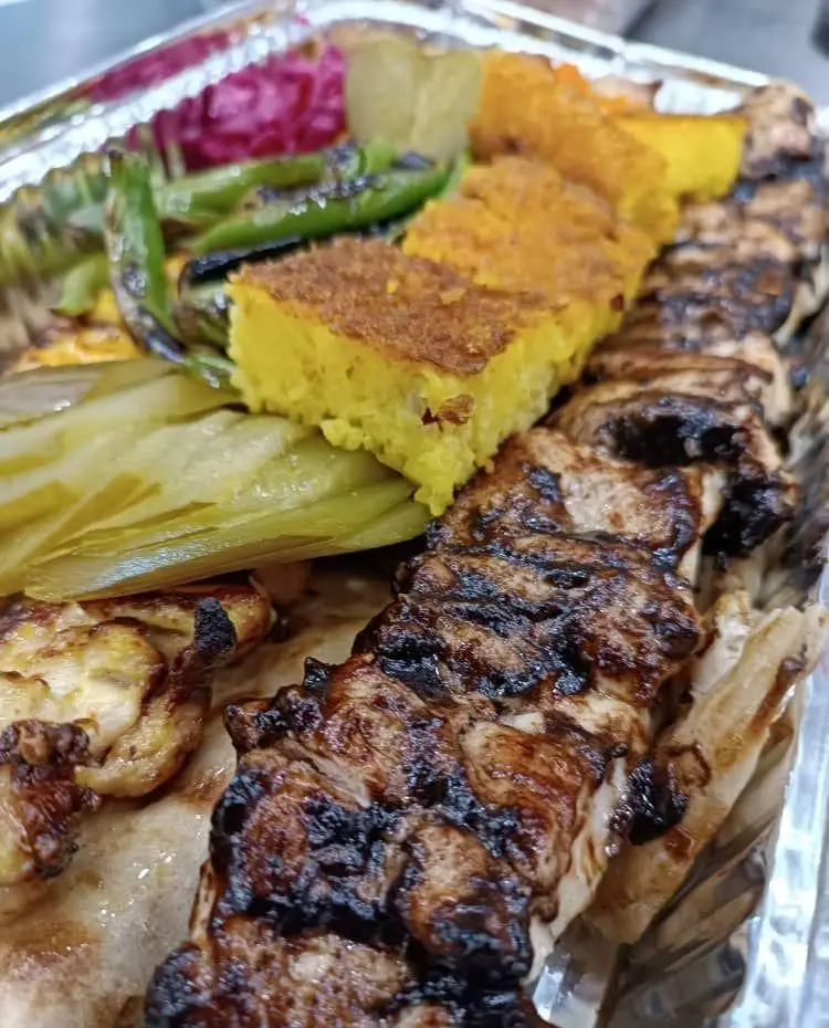 جوجه کباب لذیذ تهران کباب با ته چین زعفرانی، فلفل کبابی و ترشی، آماده ارسال و لذت بردن از یک غذای ایرانی خوشمزه.