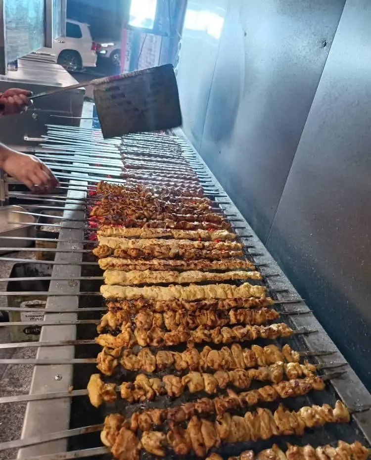 پخت کباب‌های خوشمزه در تهران کباب؛ ردیف‌های طولانی جوجه کباب و کوبیده روی منقل داغ، آماده سرو برای مشتریان.