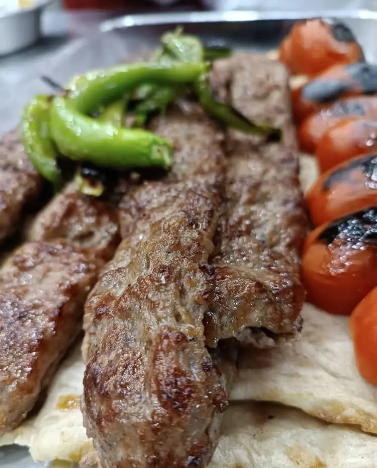 کباب کوبیده لذیذ تهران کباب با گوجه کبابی و فلفل سبز، سرو شده بر روی نان تازه، غذایی اصیل و خوشمزه از آشپزی ایرانی.