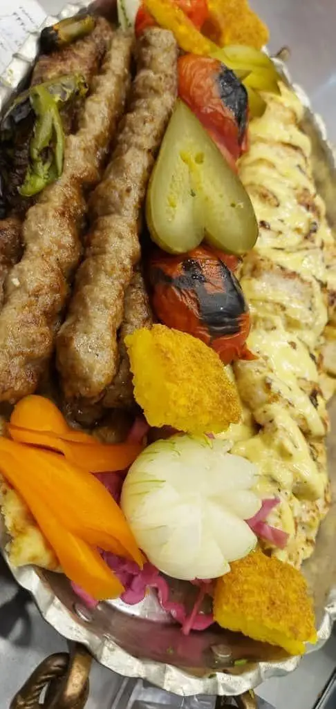 تجربه کباب اصیل ایرانی در تهران کباب: سینی ویژه شامل کوبیده و جوجه کباب، همراه با گوجه کبابی، پیاز و ترشیجات متنوع.