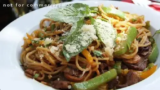 یک بشقاب اسپاگتی خوشمزه با تکه های گوشت گوساله، فلفل دلمه ای رنگی، قارچ و تزئین شده با پنیر و ریحان در کافی شاپ چهارچوب.