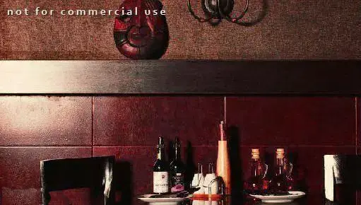 تصویری از محیط داخلی کافی شاپ چهارچوب با دکوراسیون شیک و دیوارهای قرمز شرابی. میزی با بطری‌های نوشیدنی و ظروف، فضایی گرم و دلنشین.