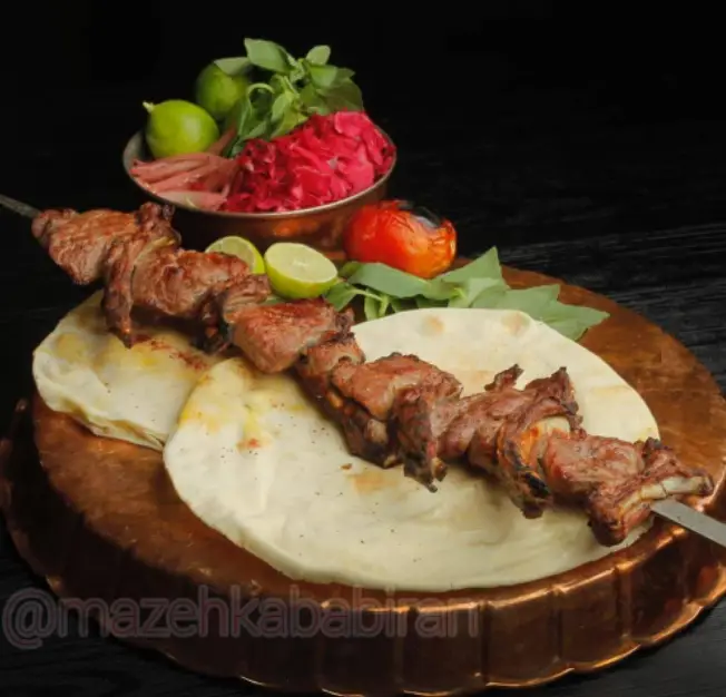 کباب چنجه گوشت لذیذ و آبدار رستوران مزه کباب گیشا با نان داغ، لیمو، گوجه کبابی و سبزی تازه. غذای اصیل ایرانی.