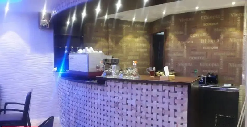فضای داخلی مدرن کافه لاوا با پیشخوان طرح‌دار، دستگاه قهوه‌ساز و دیوارپوش‌های منقش به کلمات مرتبط با قهوه، آماده سرو نوشیدنی‌های گرم.