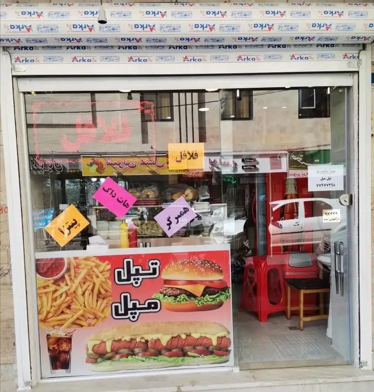 نمای بیرونی فست فود تپل مپل با ویترین شیشه‌ای، تبلیغات همبرگر، پیتزا، هات داگ و فلافل، همراه با سیب زمینی سرخ کرده