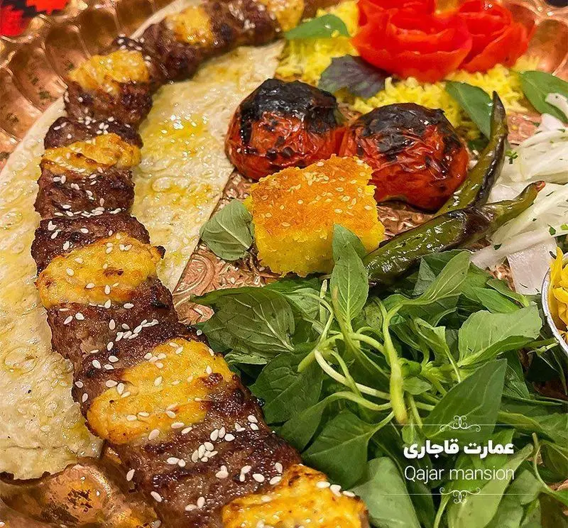 سفره سنتی و زیبای رستوران عمارت قاجاریه با کباب کوبیده زعفرانی، برنج، گوجه و فلفل کبابی، نان و سبزیجات تازه.