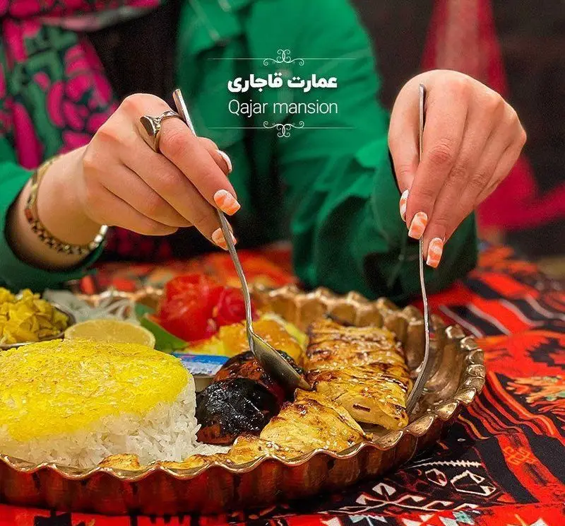 نمای نزدیک از سرو غذای سنتی و لذیذ در رستوران عمارت قاجاریه، شامل کباب مرغ و برنج با زعفران، برای تجربه غذاخوری اصیل ایرانی.