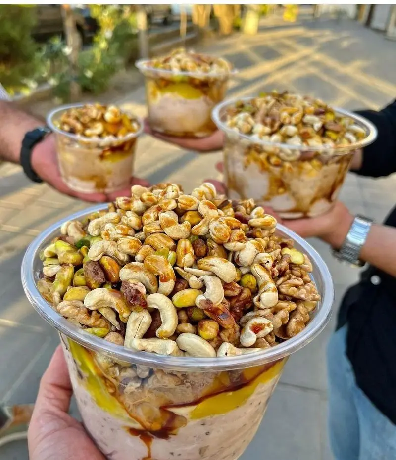 خشکبار خاتون: دسرهای اشتهاآور با رویه‌ای پربار از مغزهای تازه شامل بادام هندی، گردو و پسته در پیمانه‌های شفاف و سس شیرین.