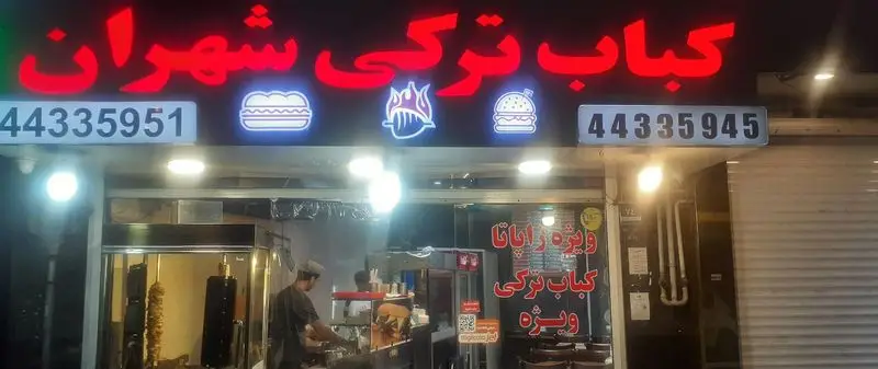 رستوران کباب ترکی شهران، نمای شب با تابلوی نئون قرمز و نمادهای همبرگر و کباب ترکی. شامل شماره تلفن 44335951 و 44335945. آماده سازی دونر کباب.