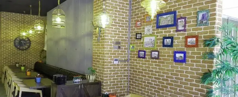 دکوراسیون داخلی دنج و جذاب رستوران برگر تهران برگر با دیوار آجری، نورپردازی خاص و قاب عکس‌های رنگی، فضایی ایده‌آل برای لذت برگر.